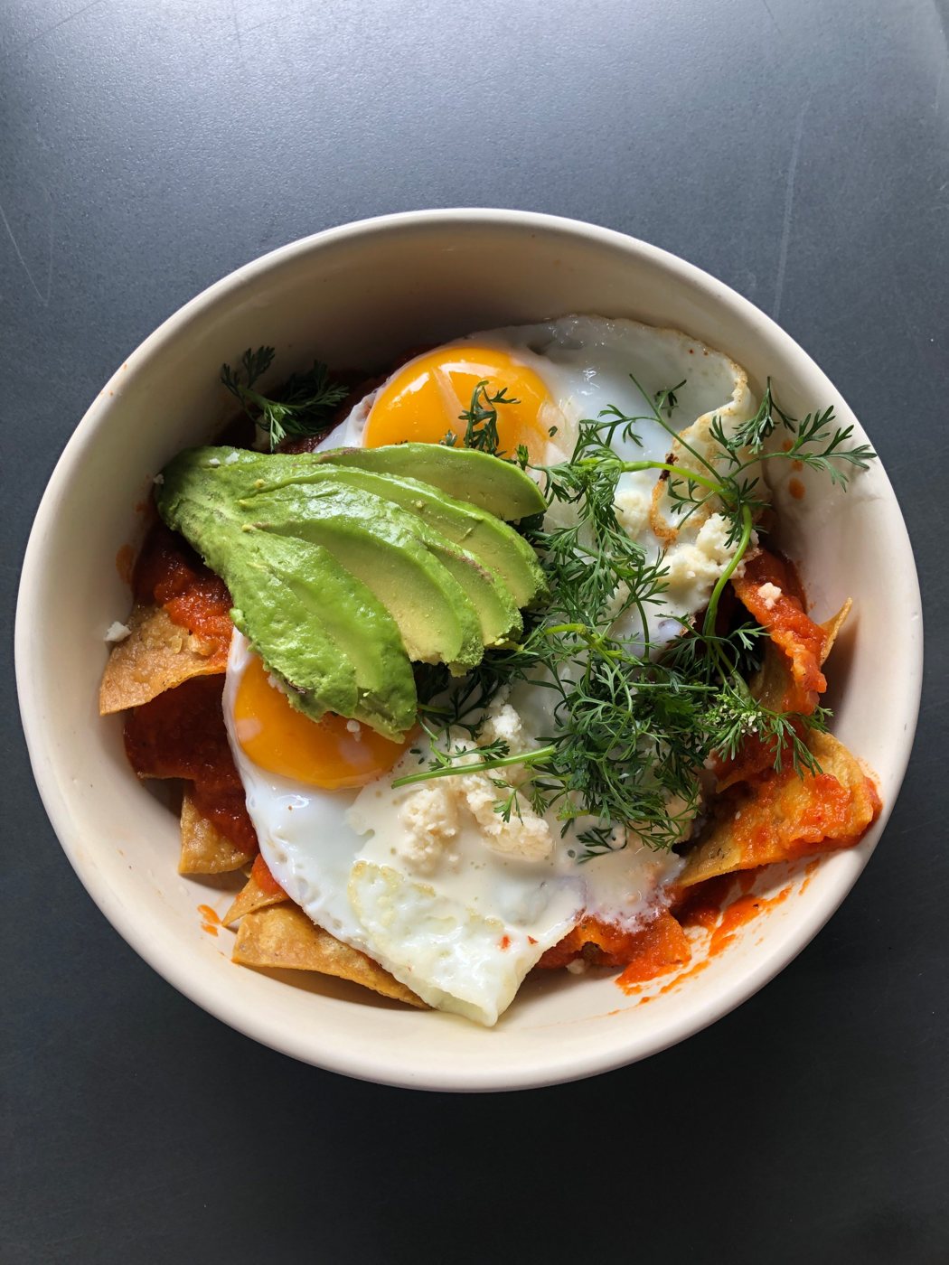 Chilaquiles topped with eggs, avocado and fresh herbs
